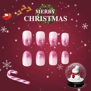 Detail of pink gradient glitter press-on nails with snowflake accents and oval shape