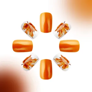 Macro view of short square autumn nails featuring maple leaf patterns and glossy orange color