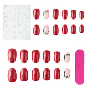 Detail view of red glitter Christmas press-on nails with leaf art, glue, and a nail file