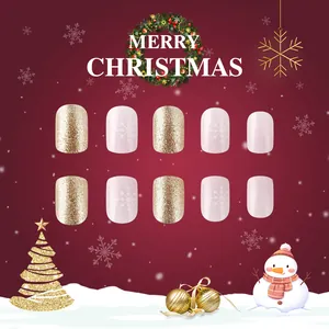 Detail of Christmas press-on nails featuring golden glitter and white snowflake patterns