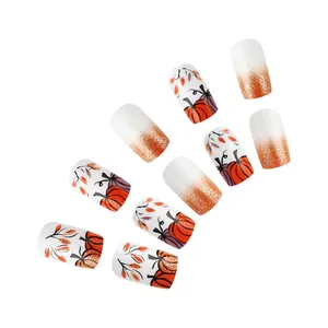 Macro detail of pumpkin and leaf patterns on short square press-on nails with orange glitter
