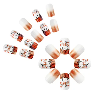Detailed view of short pumpkin and autumn leaf pattern press-on nails with orange glitter