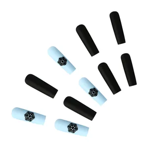 Detail of matte blue and black coffin press-on nails with festive snowflake designs