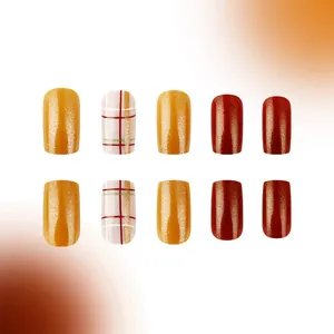 Short square press-on nails with pumpkin plaid and glitter finish in warm autumn tones