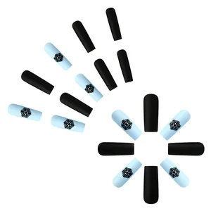 Detail of matte blue and black coffin nails with winter snowflake patterns
