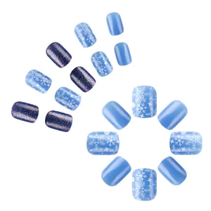 Detail of blue Christmas press-on nails with snowflake patterns and glitter finish