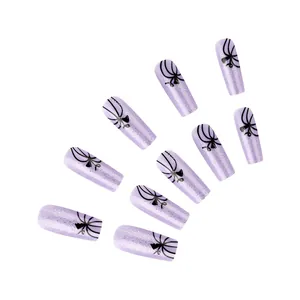 Détail de faux ongles courts violets brillants avec paillettes et motifs de lignes noires