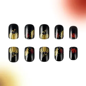 Short glossy black press-on nails with golden pumpkin and maple leaf autumn patterns