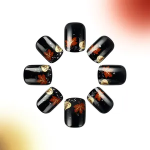 Close-up of black glossy press-on nails with red and gold autumn maple leaf designs