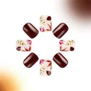 Detalle de uñas postizas cortas cuadradas con patrones de hojas de otoño y acabado granate