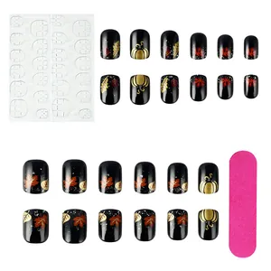 Detail of 24pcs black press-on nails with golden pumpkin and maple leaf patterns