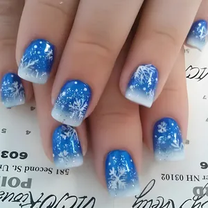 Close-up of blue and white gradient fake nails with snowflake patterns and silver glitter