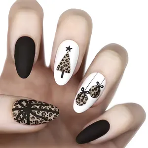 Detail of matte black and leopard print press-on nails with Christmas tree and bow motifs