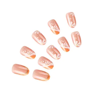 Detail of nude pink gradient press-on nails with white daisies and golden glitter tips