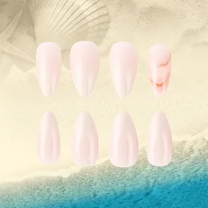 Close-up of nude pink almond press-on nails with marble texture on a beach background