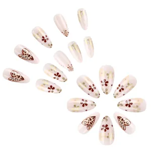 Detail view of almond press-on nails with wine red floral and gold leopard heart designs