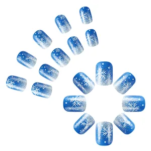 Detail of blue gradient fake nails with white snowflakes and silver glitter patterns