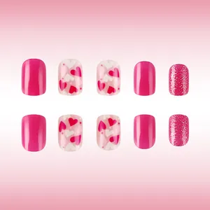 Detail of short square press-on nails featuring red glitter and heart pattern design