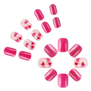 Short square press-on nails with shiny pink finish, glitter, and heart patterns for Valentine