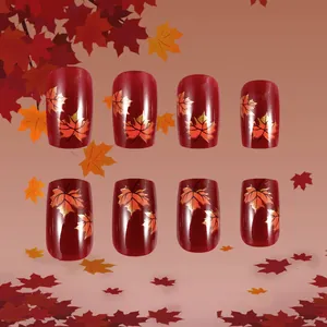 Detailed view of dark red maple leaf press-on nails with golden glitter accents for autumn