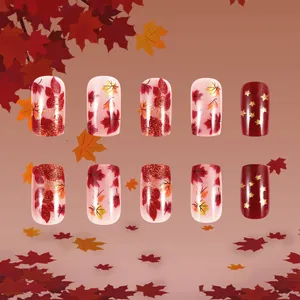 Detail of medium square press-on nails featuring maple leaf and star autumn motifs