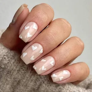 Vue détaillée de faux ongles carrés brillants avec des motifs de cœurs blancs