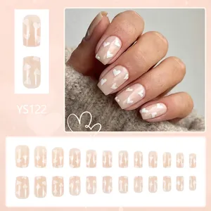 Faux ongles courts carrés brillants avec motifs cœurs blancs sur fond rose nude