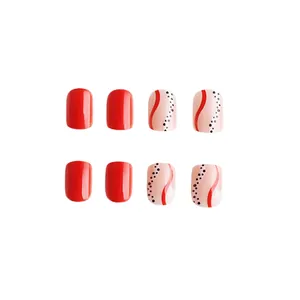 Détail de faux ongles carrés rouges brillants avec motifs de vagues et pois noirs
