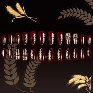 Detailed view of deep red almond press-on nails featuring golden wheat ear patterns