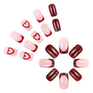 Short square press-on nails with pink heart patterns and red glitter finish