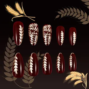Short almond press-on nails in deep red with elegant golden wheat ear patterns