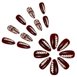 Short almond press-on nails in glossy deep red with gold wheat ear pattern design