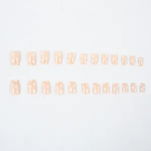 Détail de 24 faux ongles carrés courts avec motifs de cœurs blancs sur base nude brillante