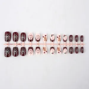 Macro detail of 24pcs Christmas press-on nails with glitter red and snowflake patterns