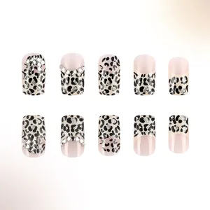 Dettaglio di unghie finte leopardate con glitter argento e strass brillanti su base rosa