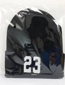Dettaglio berretto in maglia nera con ricamo bianco numero 23 nella confezione