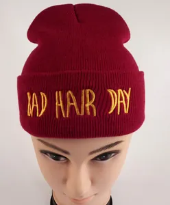Détail de la broderie jaune Bad Hair Day sur un bonnet en maille tricoté bordeaux