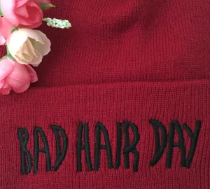 Détail du bonnet en tricot bordeaux avec broderie Bad Hair Day et décoration florale