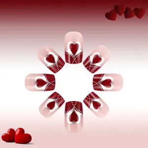 Macro shot of square-oval fake nails with red hearts and silver polka dots on pink base
