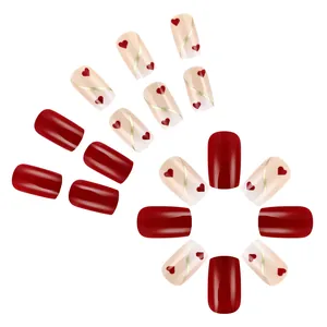 Faux ongles carrés courts avec cœurs rouges et lignes dorées sur dégradé rose