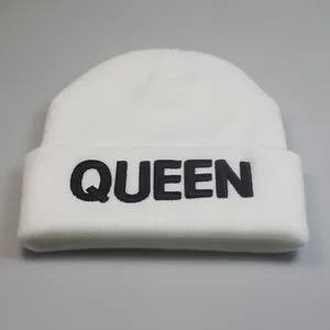 Detailaufnahme der weißen Strickmütze mit schwarzer QUEEN-Stickerei auf dem Umschlag