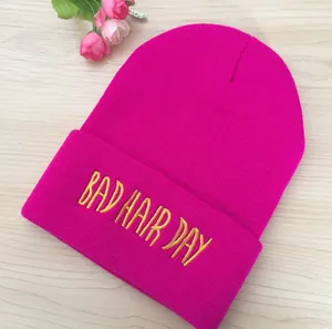 Gros plan détaillé de la broderie jaune Bad Hair Day sur un bonnet en tricot rose