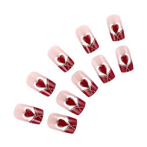Detail of medium square press-on nails featuring red tips and silver heart patterns
