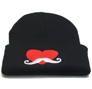 Close-up of heart and mustache embroidery on a black ribbed knit beanie hat