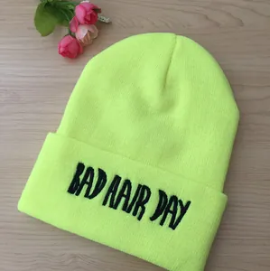 Gros plan sur un bonnet en tricot vert néon avec broderie Bad Hair Day noire sur bois