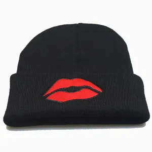 Detailed close-up of the red lip embroidery on a black knitted winter beanie hat
