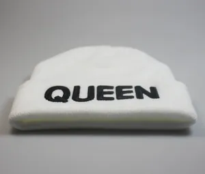 Detailansicht der weißen Strickmütze mit schwarzem QUEEN-Stickmuster auf dem Umschlag