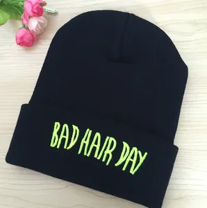 Détail de la broderie verte Bad Hair Day sur un bonnet en maille noire à revers