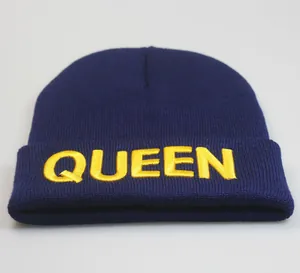 Detail der gelben QUEEN-Stickerei auf einer dunkelblauen Strickmütze für den Winter