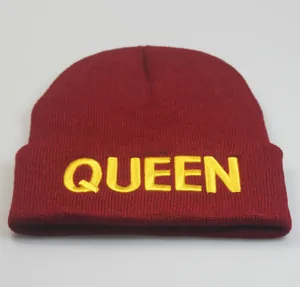 Detail der gelben Queen-Stickerei auf einer weinroten gerippten Strickmütze